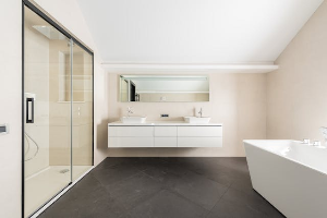 Un baño moderno con ducha con mampara de cristal, un mueble de baño con espejo y una bañera de cerámica blanca.